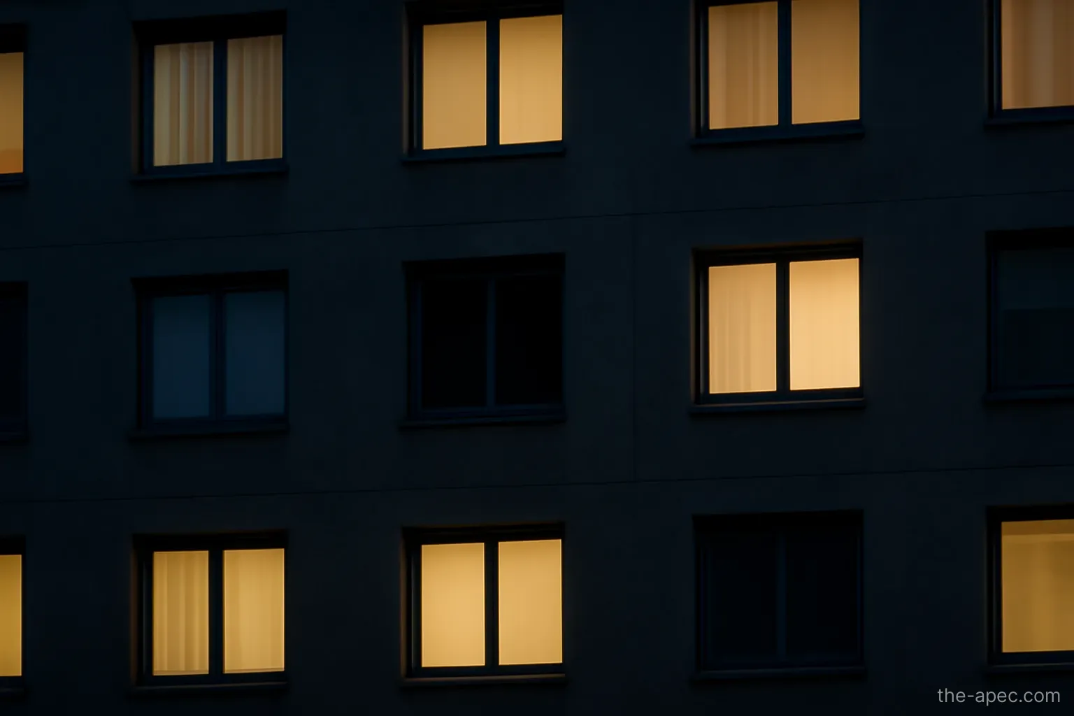 a single unlit window in a building facade at night while others are lit, no signage